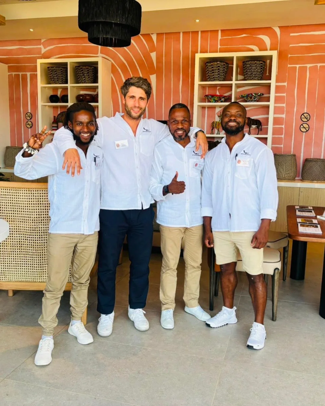 Four team members wearing custom white embroidered button-up shirts in a hospitality setting, Handmade shirts by Soli in Cape Town for staff merchandise.