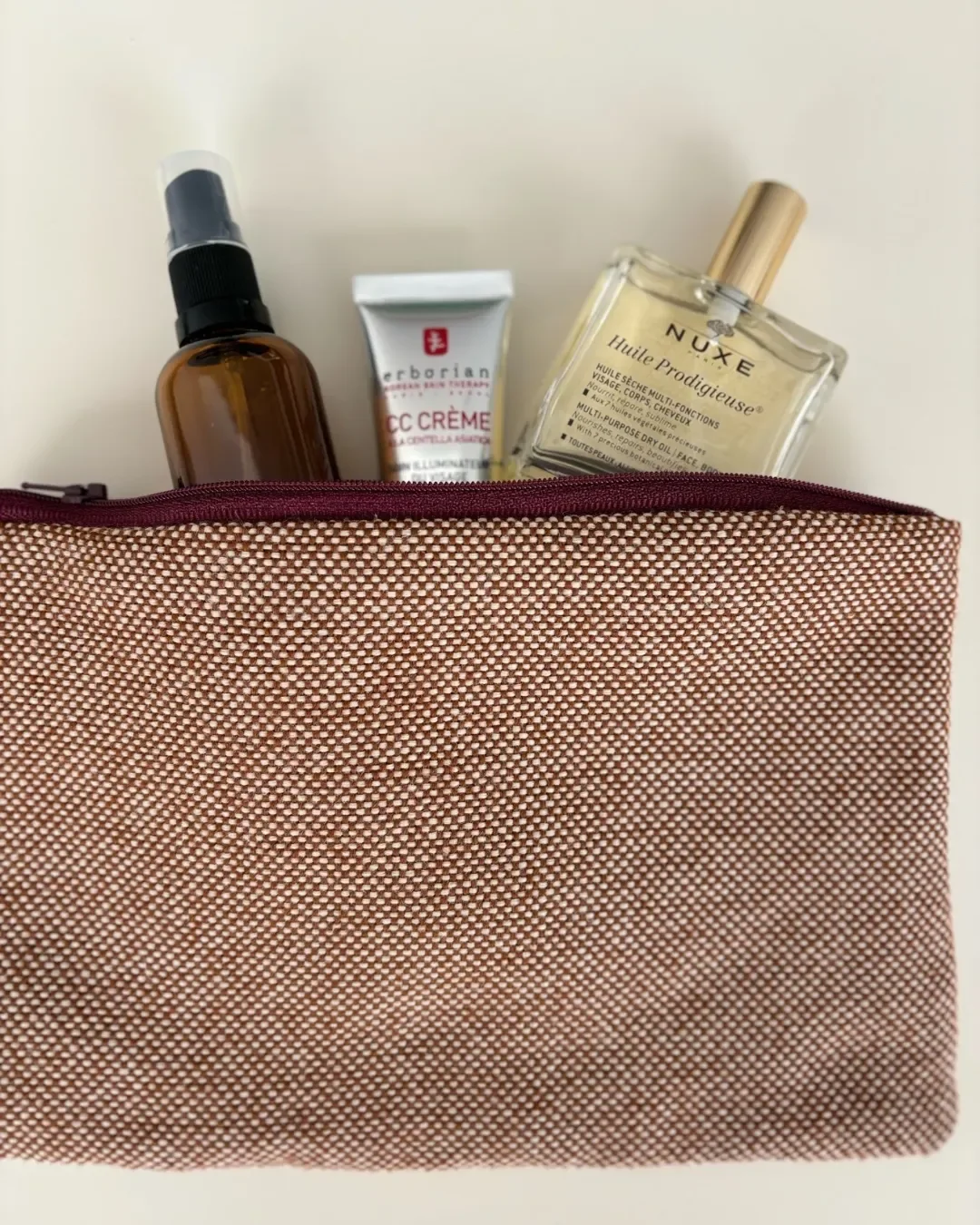 Refined Serengeti pouch made from 100% natural fibre with a maroon zip, filled with cosmetic amenities, handmade in Cape Town by Soli.