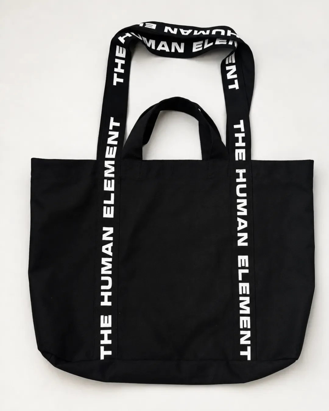 Overhead flat lay of a black dual carry canvas tote bag with two sets of handles on a clean white surface, Handmade by Soli in Cape Town for branded merchandise or corporate gifts