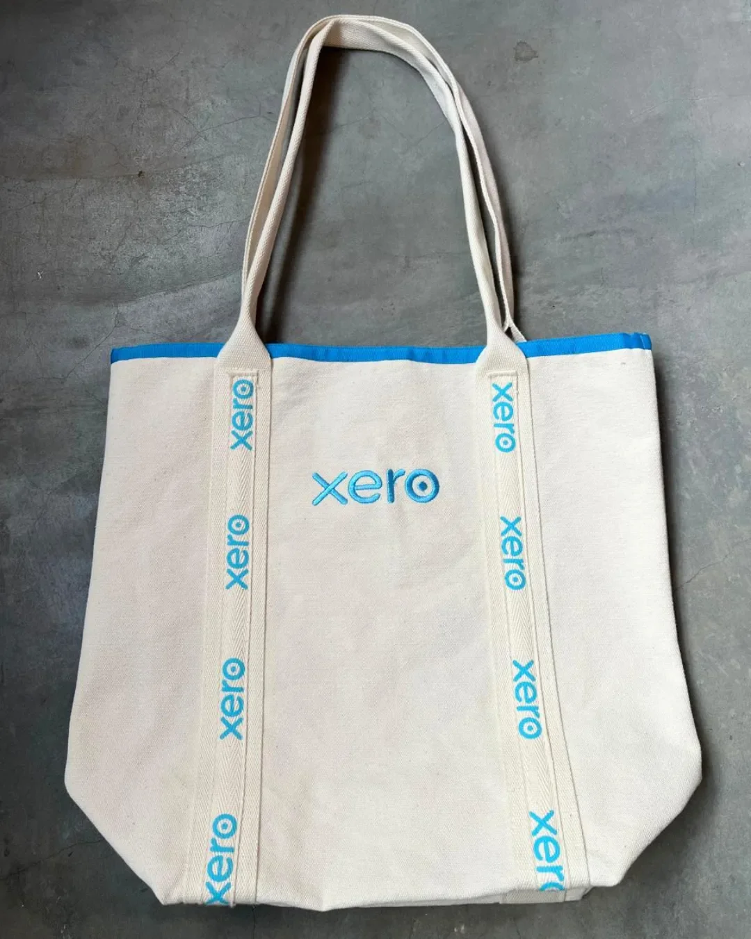 A full view of the cream Promenade tote bag made from 100% cotton canvas with blue Xero logo embroidery on the front and straps, handmade by Soli in Cape Town for sustainable merchandise or corporate gifts.