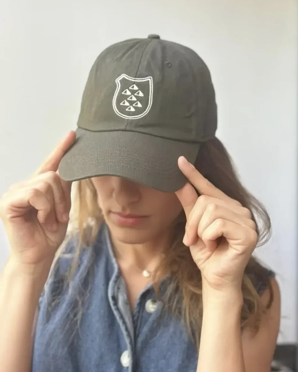 Close-up of the front of a custom cream-colored cap featuring a wavy, bright pink embroidered "Meta Lab" logo, worn by a person wearing a vibrant pink button-up shirt. .
