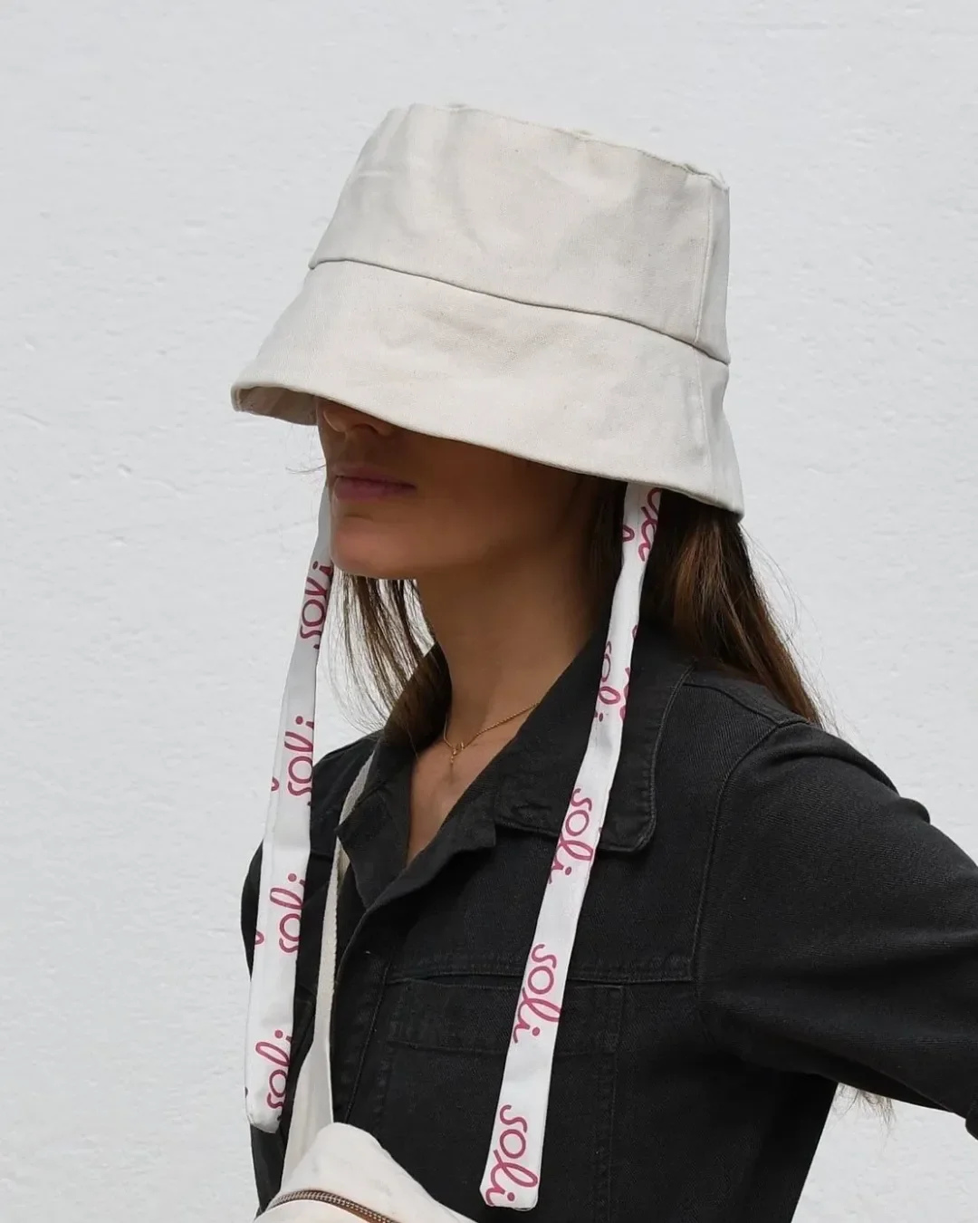 Woman wearing a Soli custom heavy canvas bucket hat in cream with branded logo ribbons, handmade in Cape Town as a sustainable corporate gift.