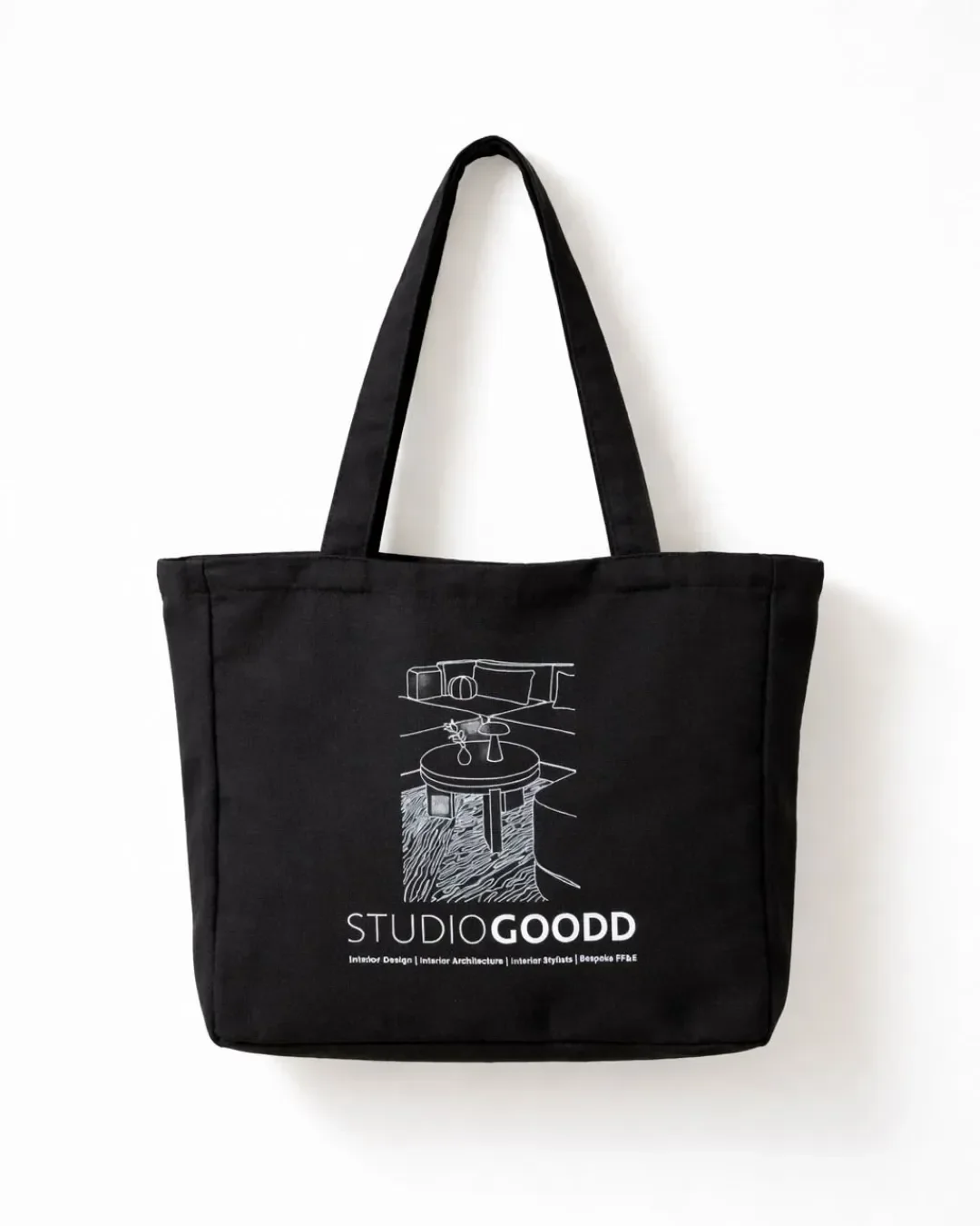 A black canvas corporate tote bag custom printed with a white line-art logo for Studio Goodd, hanging against a clean white background for high-end promotional merchandise.
