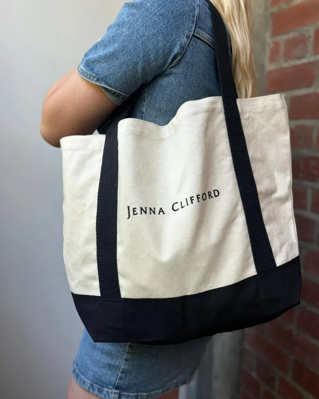 Custom embroidered Milano Tote in heavy cream canvas with black handles and base, featuring Jenna Clifford branding, handmade by Soli's artisans in Cape Town for merchandise or corporate gifts.