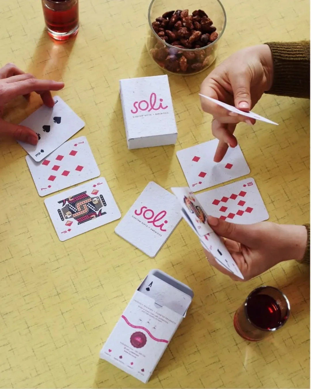 A deck of custom-branded plantable playing cards corporate gift featuring pink Soli branding, made from 100% recycled biodegradable seed paper.