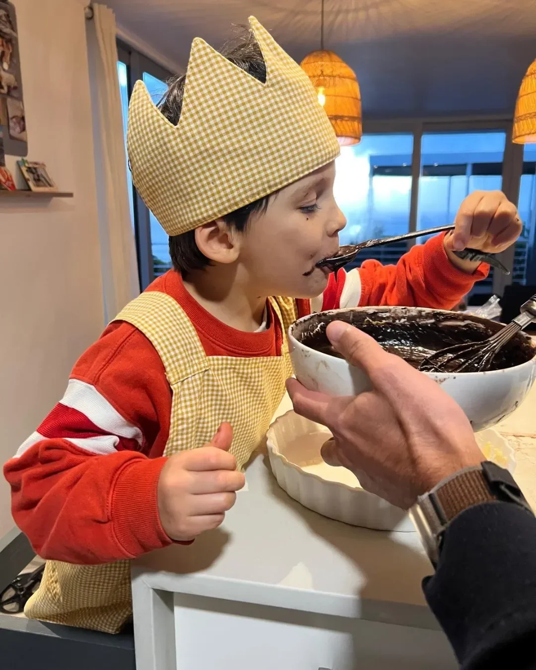 A young child wearing a yellow checkered custom crown while baking, demonstrating the playful appeal of Soli’s sustainable corporate gifts and merchandise made in cape town.