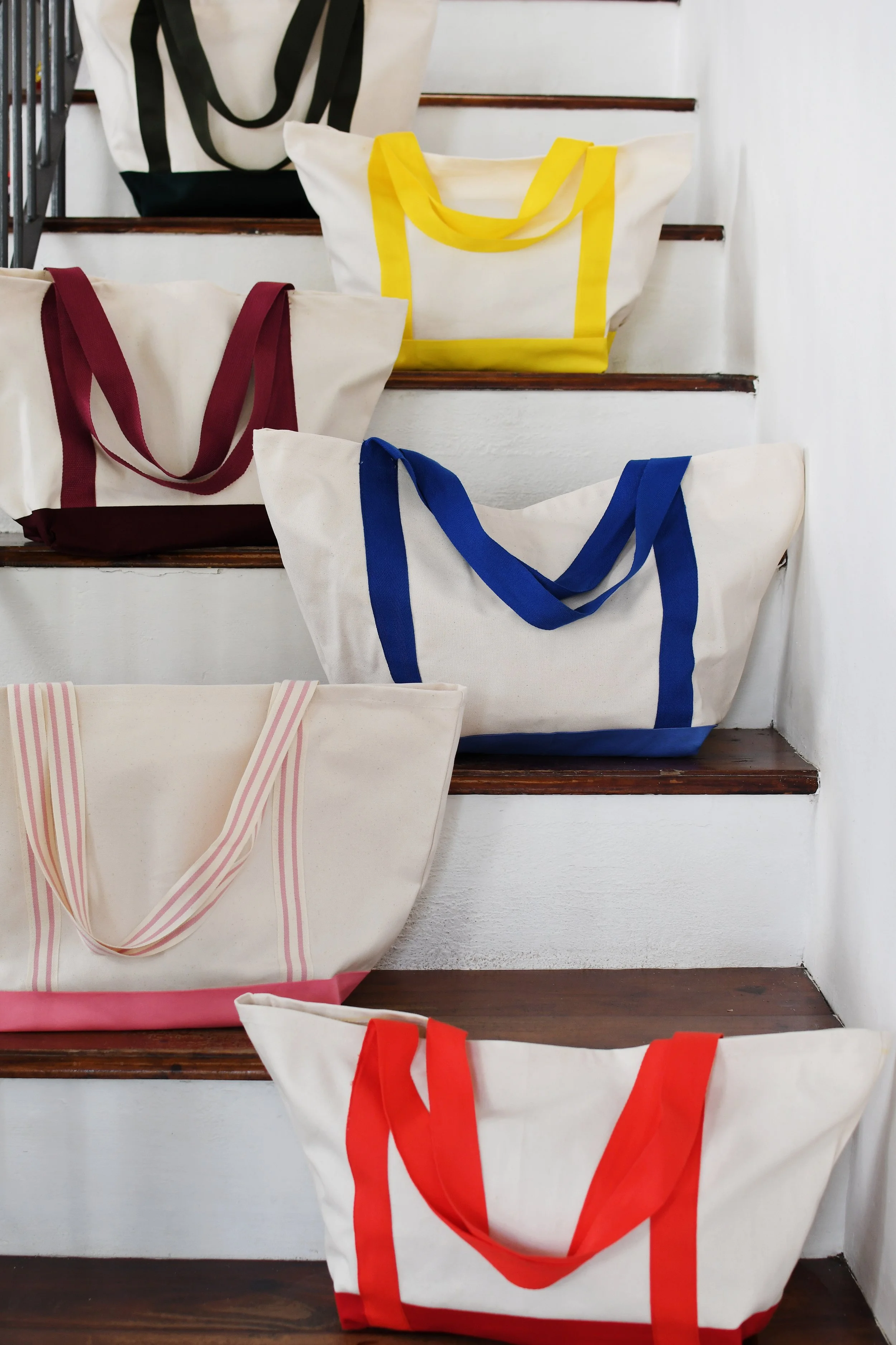 Canvas tote bags with colored handles on stairs