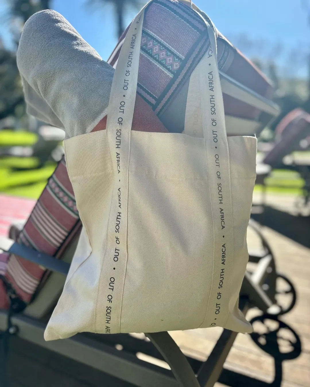 Custom branded signature strap bag in natural bull denim with personalized logo handles hanging on a chair. Handmade by Soli in Cape Town for sustainable merchandise or corporate gifts.