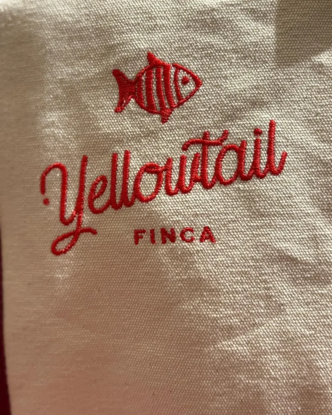 Close-up of bespoke red fish embroidery on a cream 100% cotton canvas Oxford bag. Handmade by Soli in Cape Town for sustainable merchandise or corporate gifts.