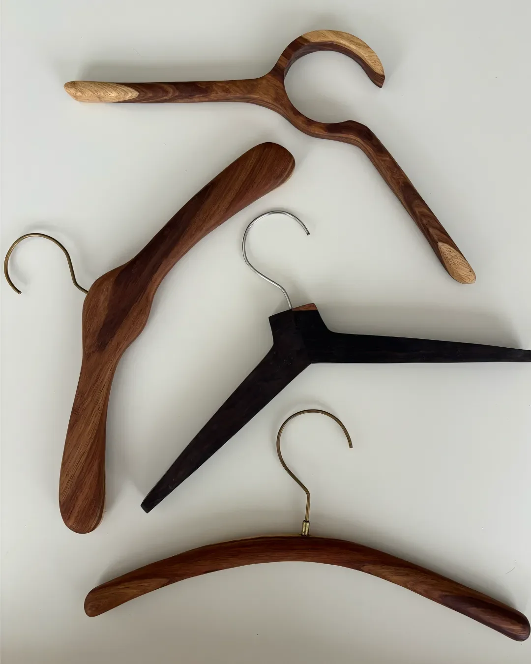 A professional, high-quality photo of Soli's custom-made wooden hanger, showcasing the natural grain of durable Kiaat wood (brown hanger) and lead wood ( black hanger ) with a beautifully finished, minimalist design.