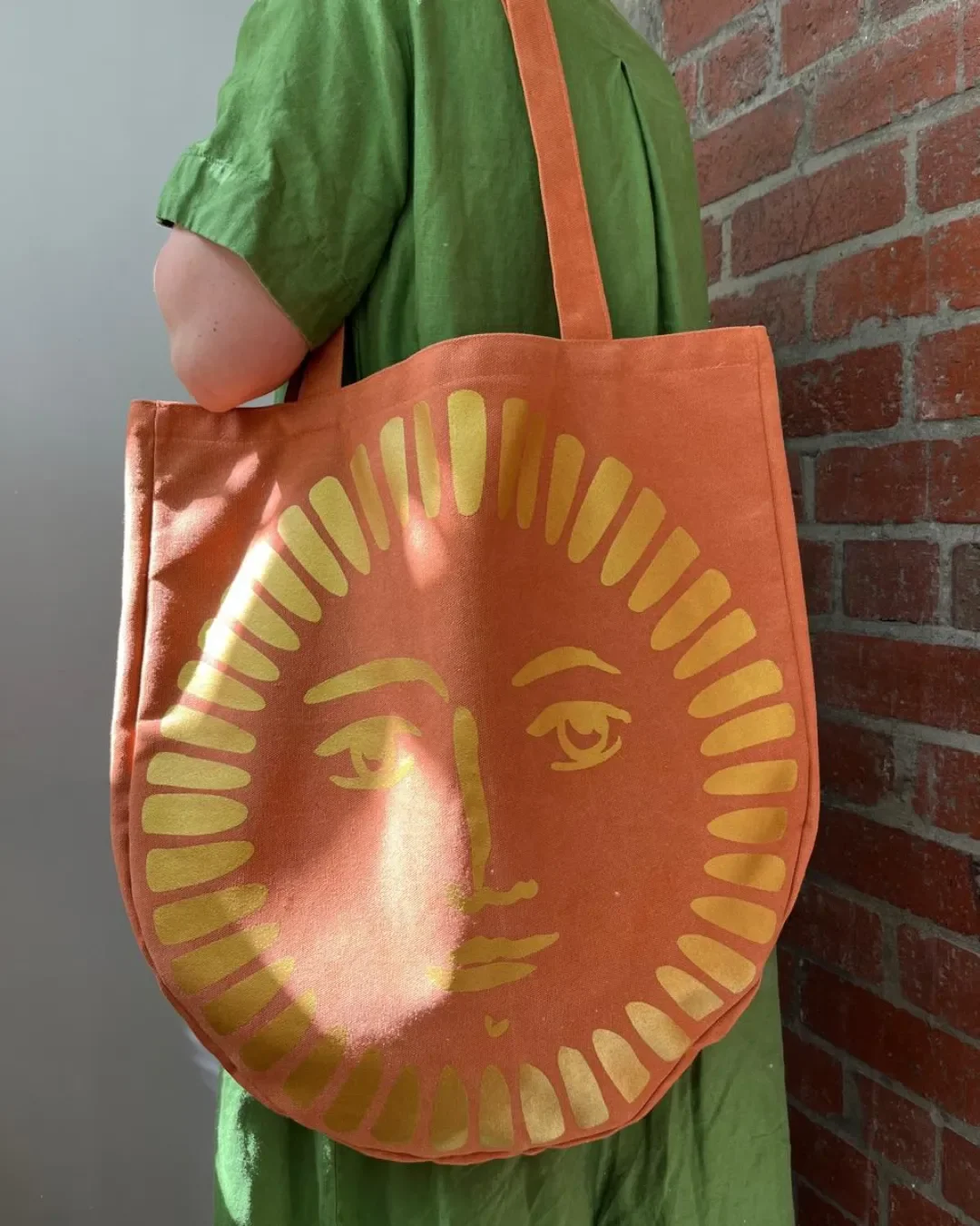Orange canvas Sun Bag featuring a yellow celestial face graphic, handmade by Soli in Cape Town for sustainable merchandise or corporate gifts.