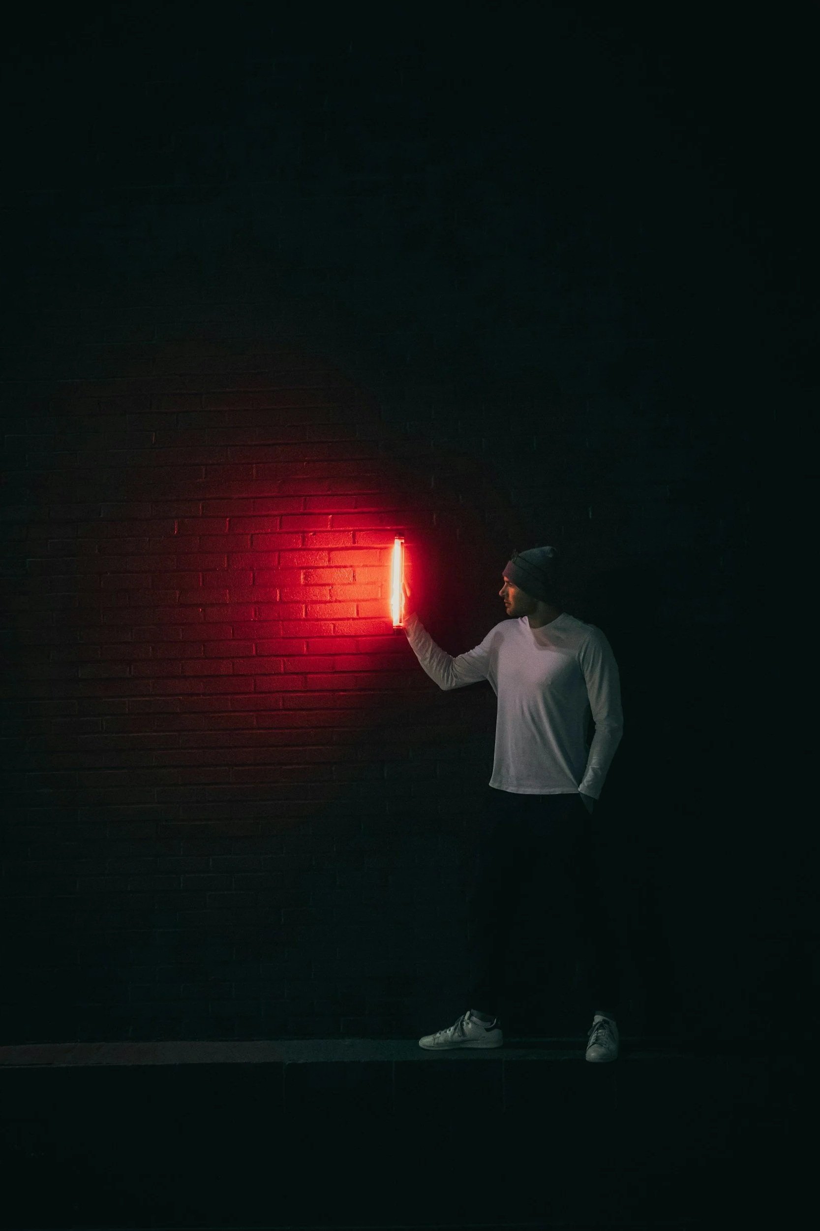 Man with red light in front of a brick wall showing direction