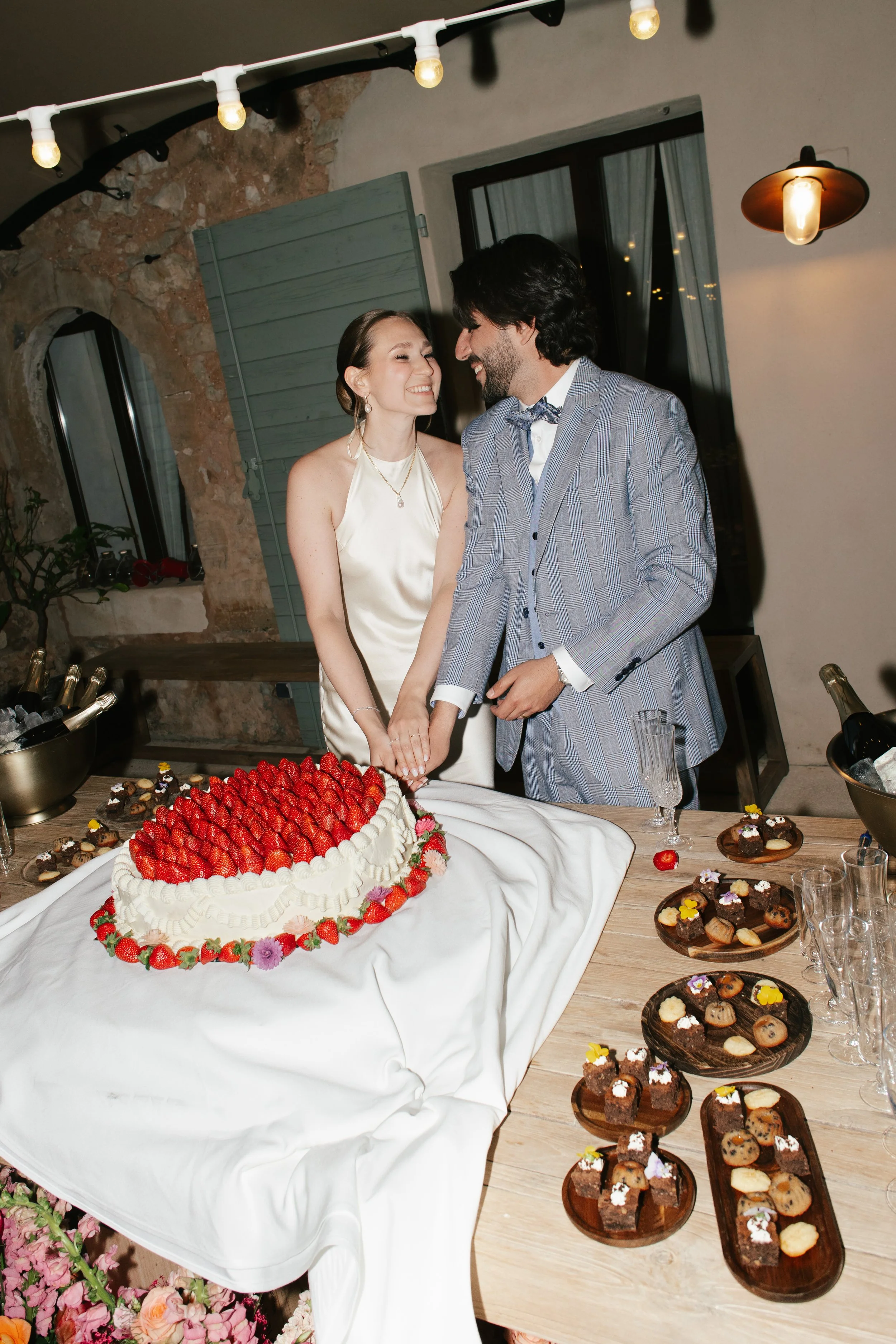 Wedding cake-cutting celebration with the bride and groom, her flawless reception makeup by Mathilde Vintze Artistry lasting beautifully into the evening festivities.