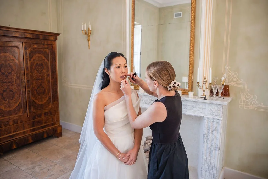Bridal makeup artist Mathilde Vintze applying lip colour to the bride by a gilded mirror on the wedding morning, Château de Beauregard, Provence