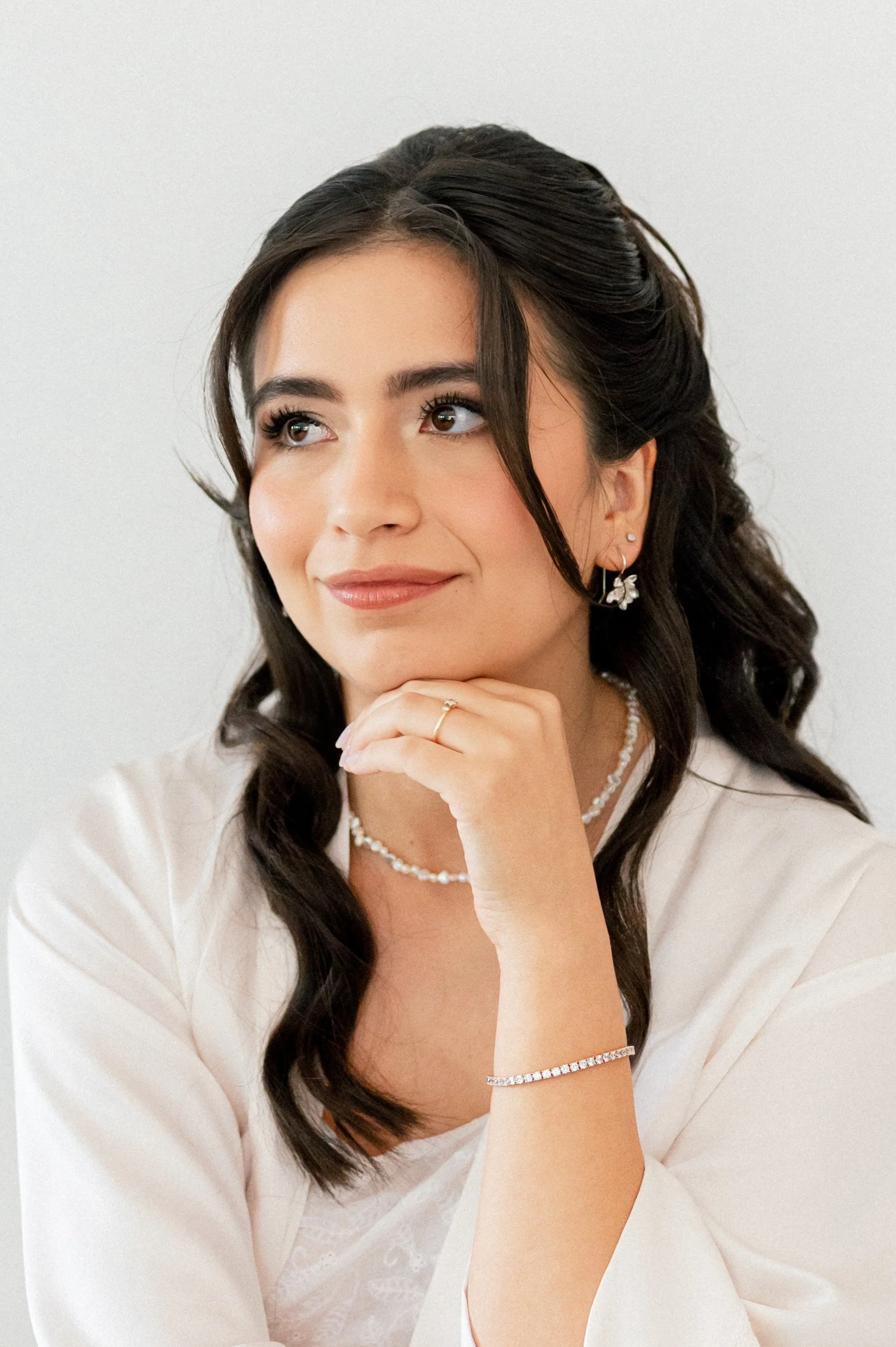 Dark-haired bride applying soft, natural wedding makeup by Mathilde Vintze, bridal makeup artist in Provence