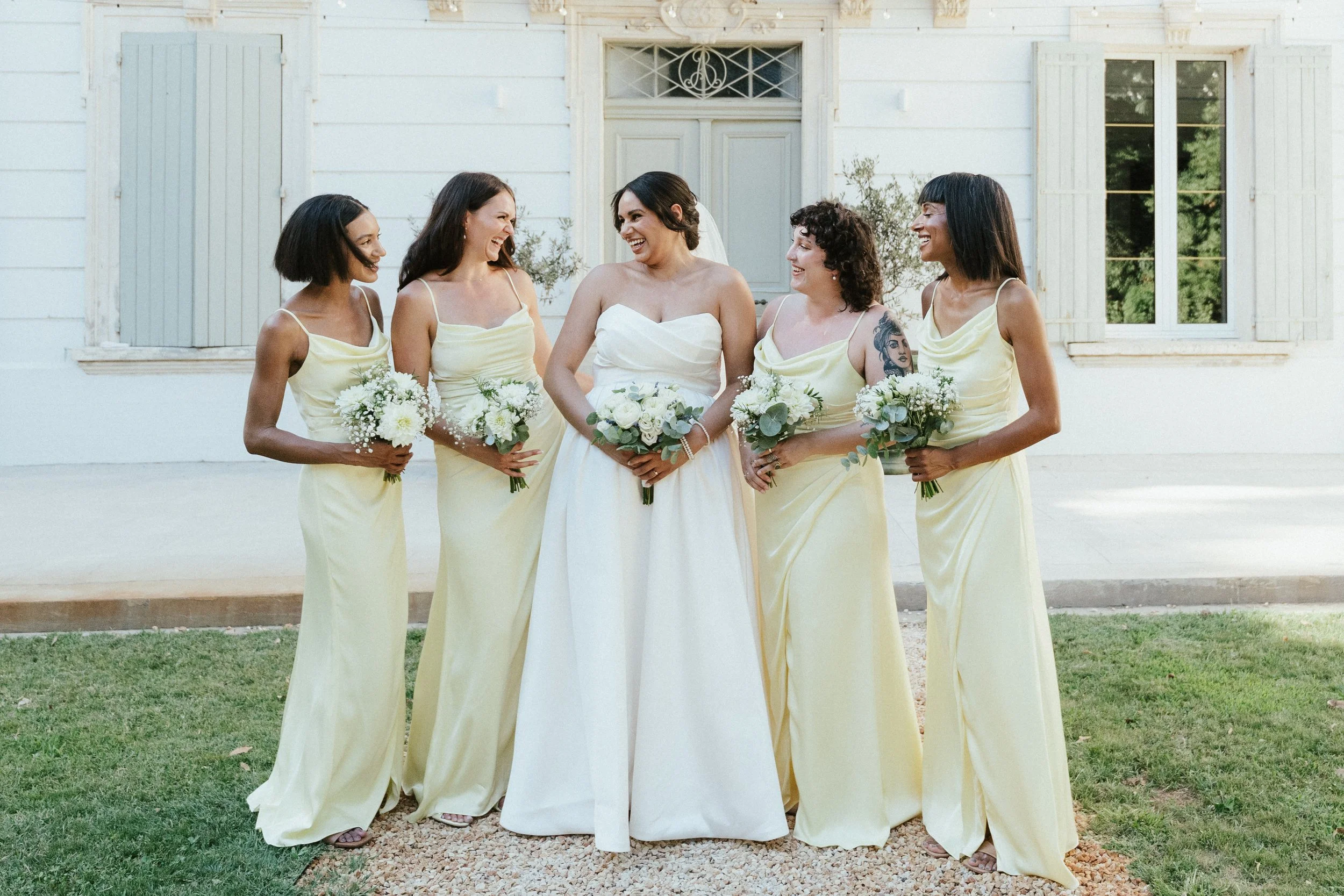 Bridesmaids in pale yellow gowns holding bouquets, soft natural makeup for the bridal party by Mathilde Vintze