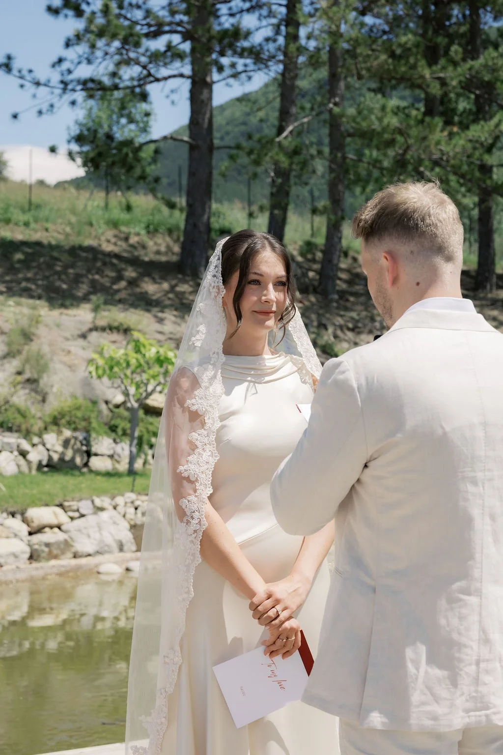 Bride and groom holding hands among the trees in Provence, the bride wearing a veil and fresh natural wedding makeup by Mathilde Vintze