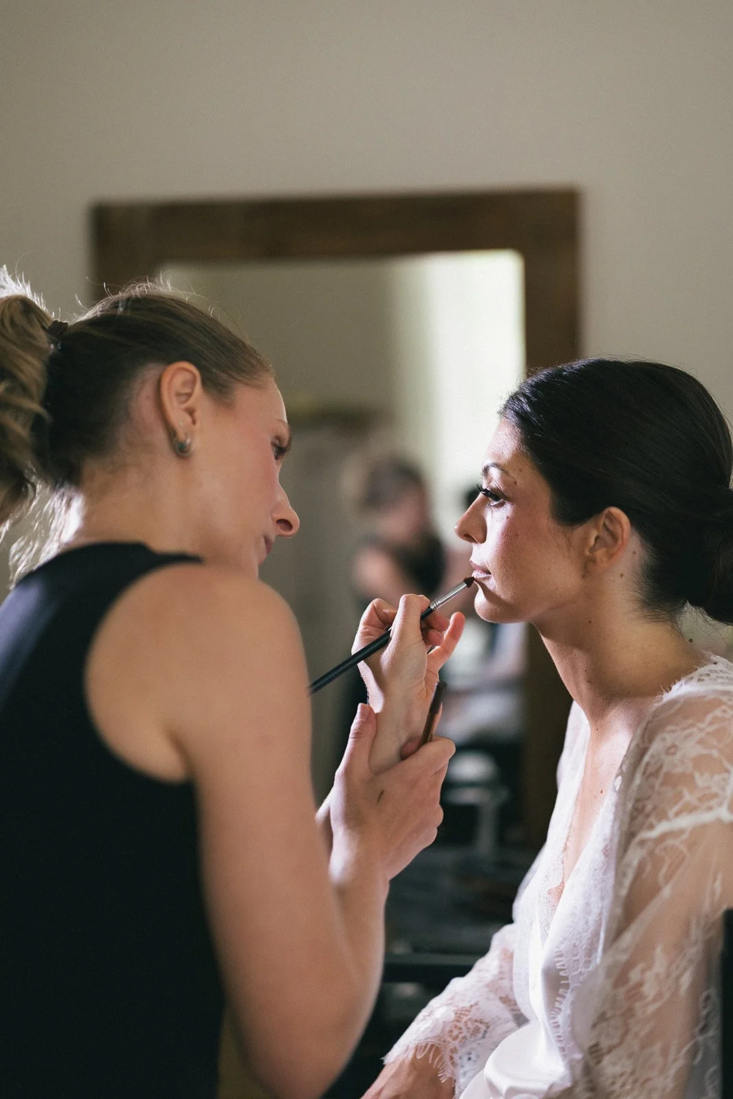 Close-up of the bride's makeup application on the wedding morning, by soft natural light. Skin-first bridal beauty at Couvent Notre-Dame des Prés, Provence.