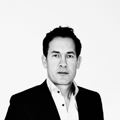 Black and white portrait of a man in a suit with a neutral expression against a plain background.