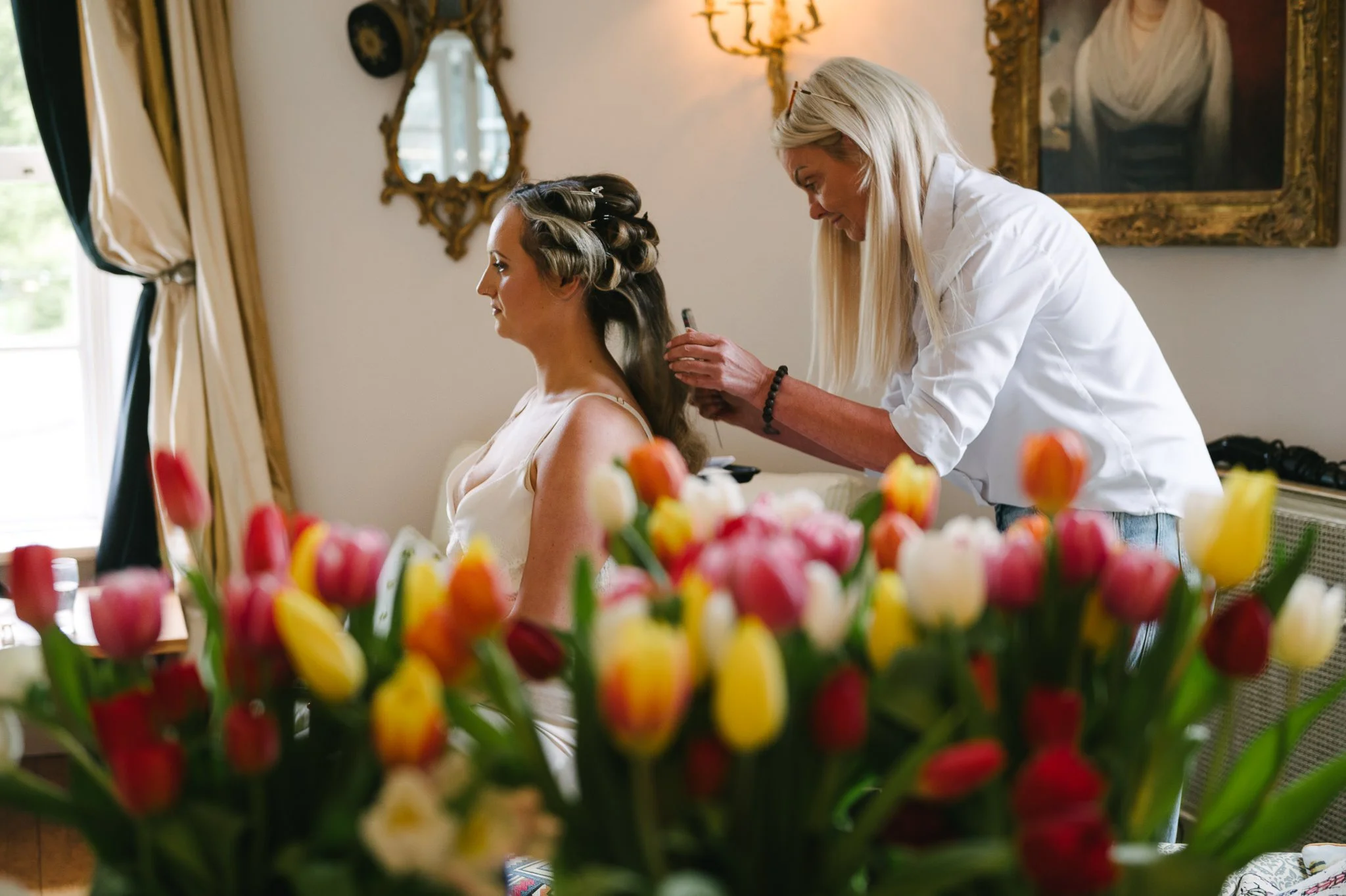 Finishing touches to the brides hair with bouquets in the foreground