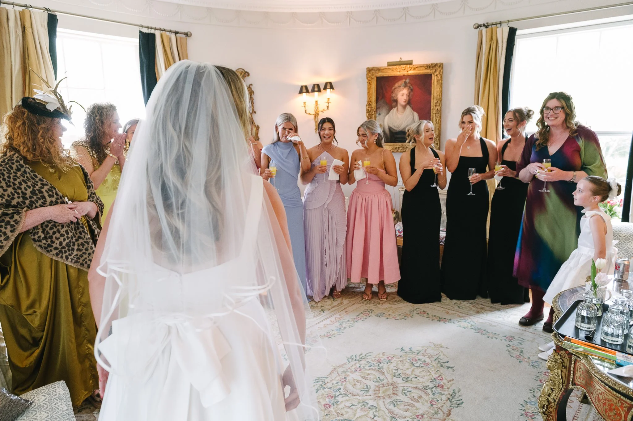 Mother of the bride and the bridesmaids seeing the bride in her dress for the first time