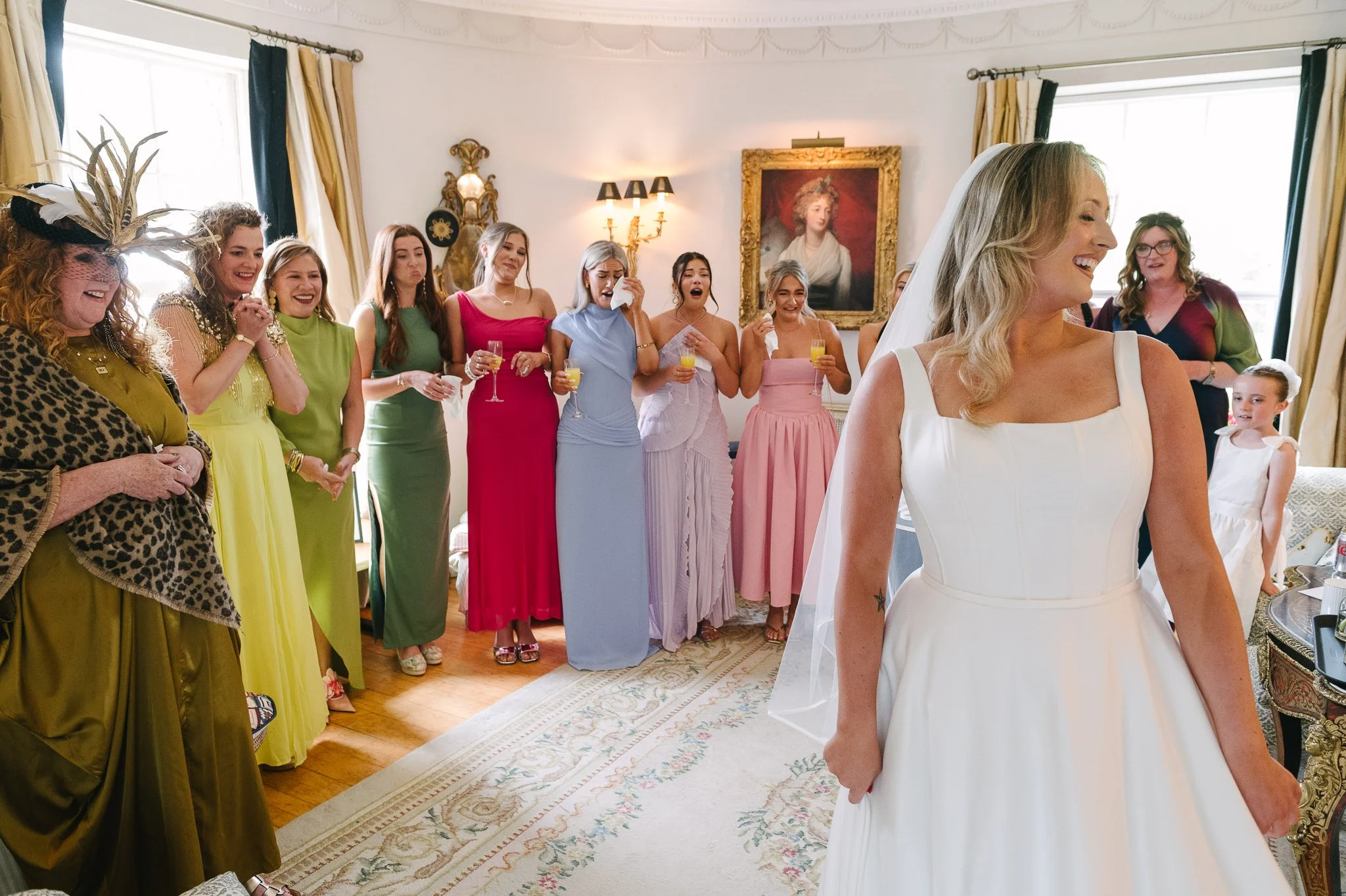 Mother of the bride and the bridesmaids seeing the bride in her dress for the first time