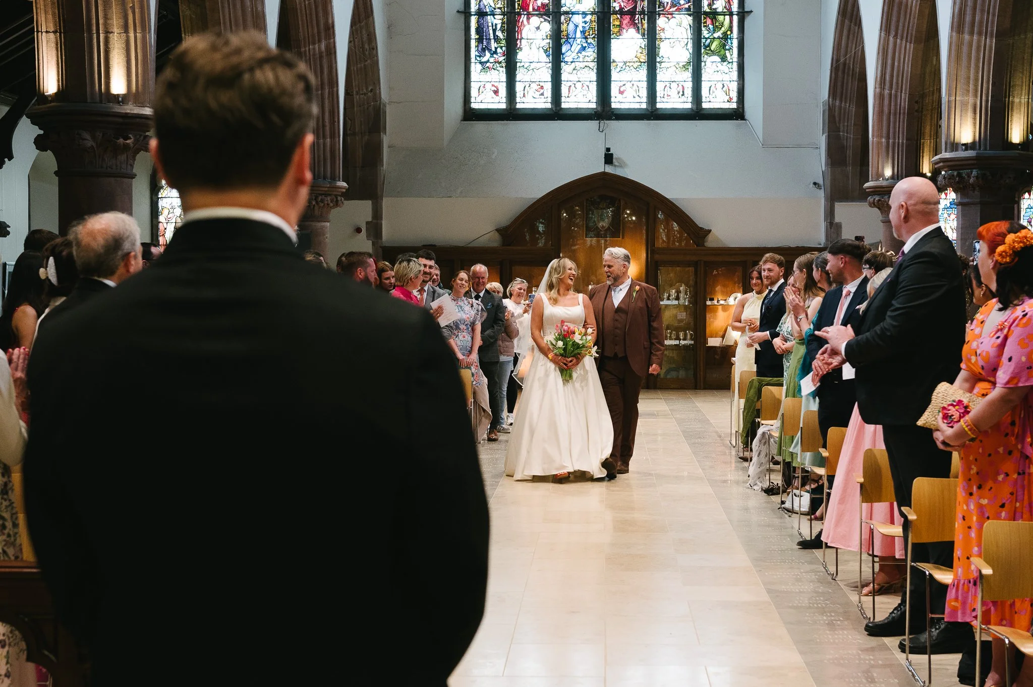 Bride and her father walking down the aisle at Peel Cathedral as the groom waits