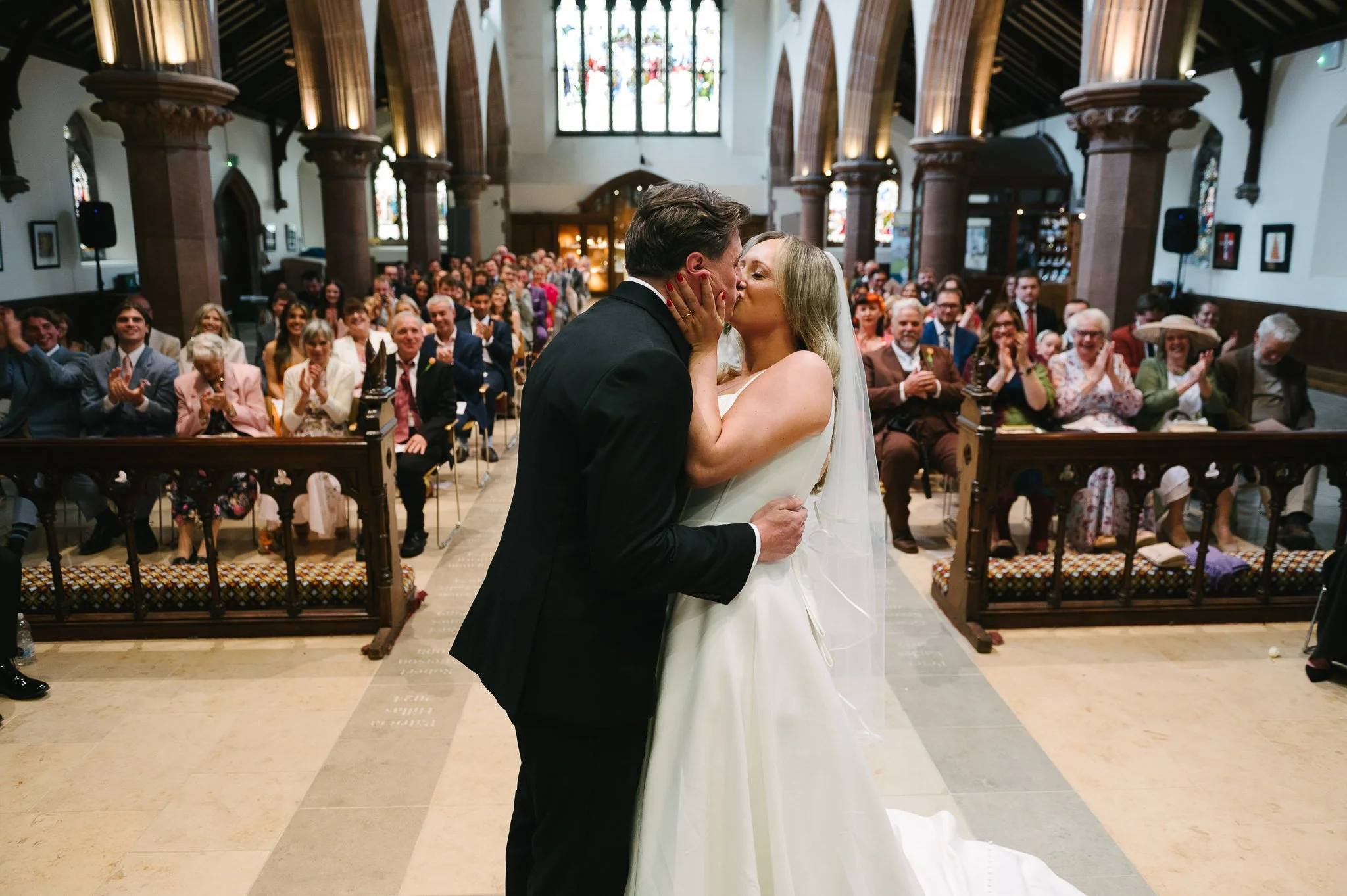 First kiss of the Bride &amp; groom in Peel Cathedral as guests clap in the background