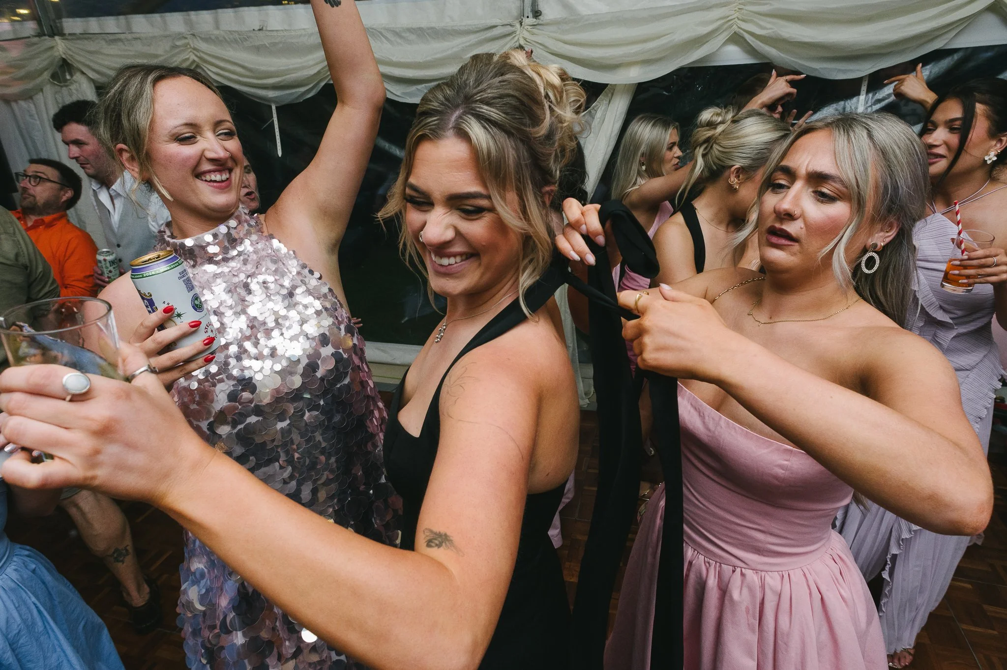 Bridesmaid continuing to dance as someone fastens her dress behind her