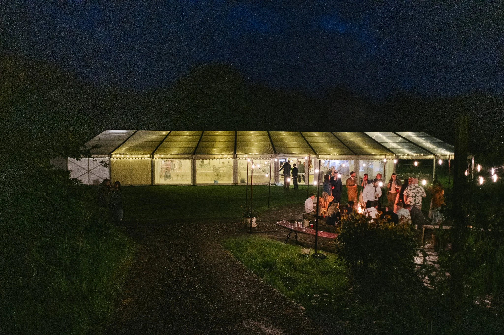 The Marquee by night at The Mill House Isle of Man wedding guests by fire pit
