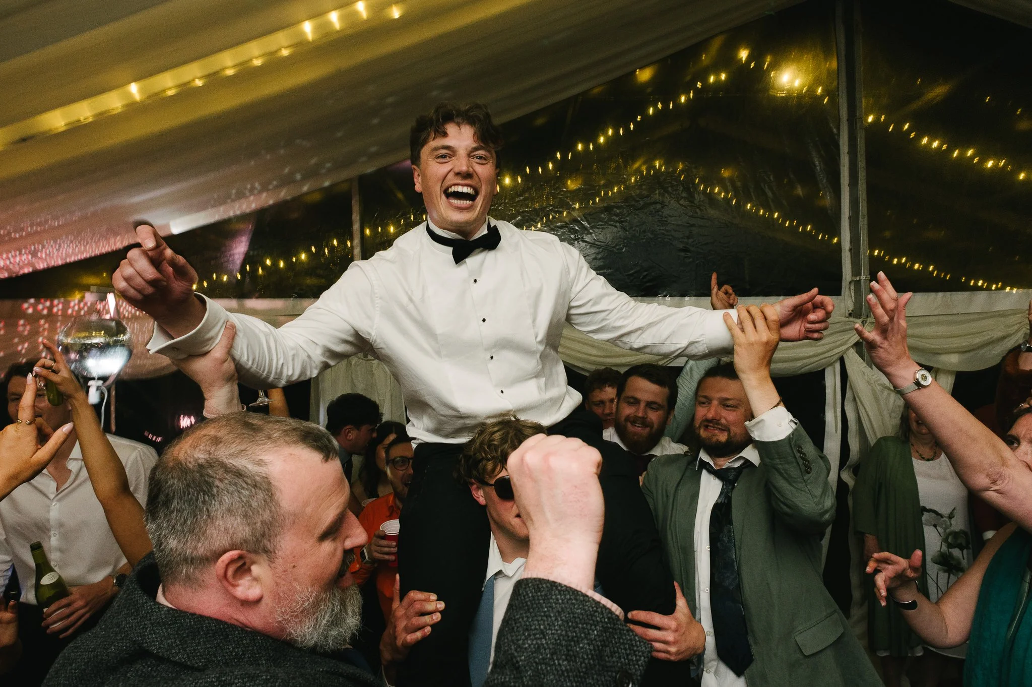 The groom sits on his brothers sholders on the dancefloor