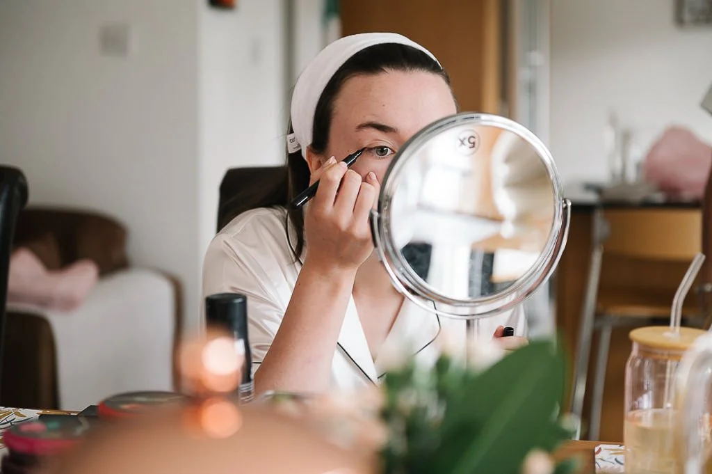 Bridesmaid applying makeup in the mirror