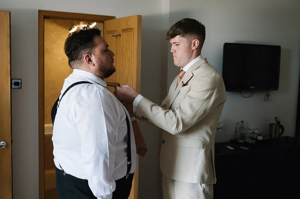 Groom sorting the best man's tie out