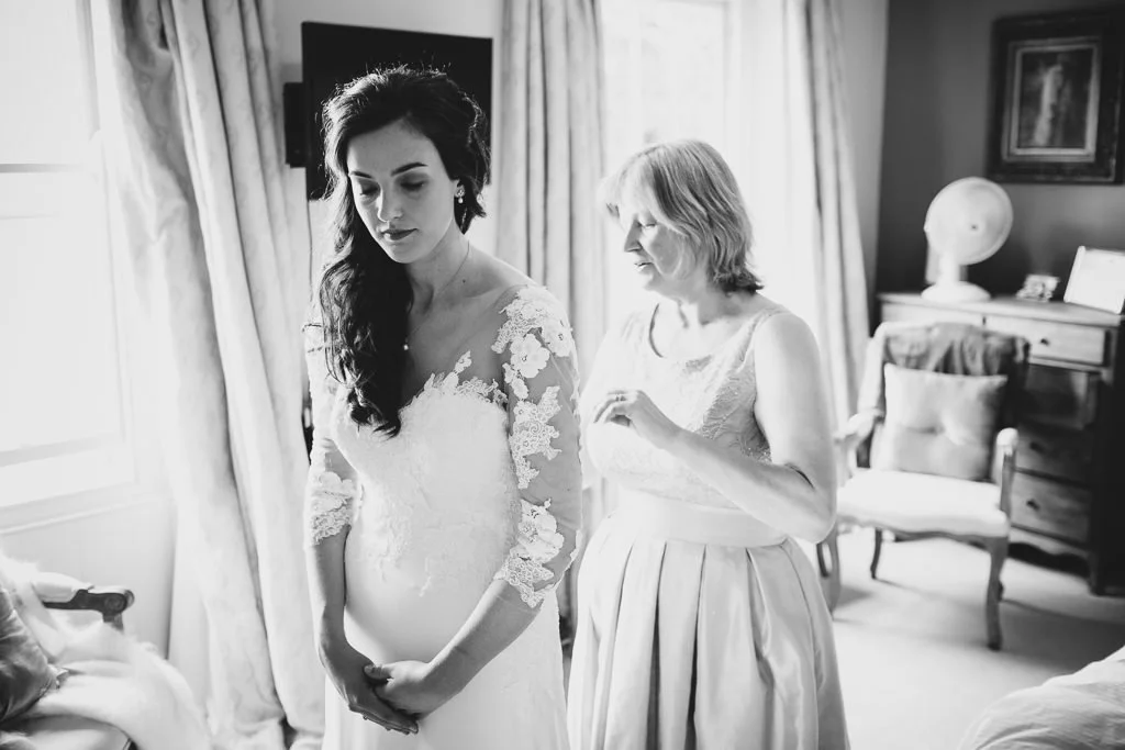 Mother of the bride fastening Becky's wedding dress