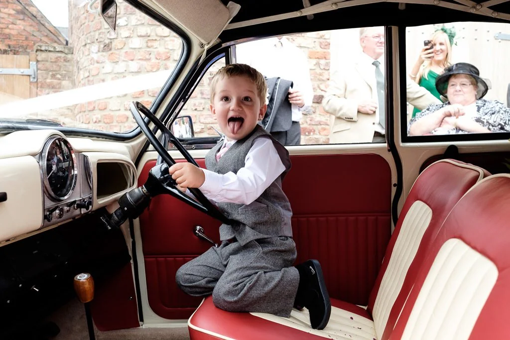 Small boy pretending to drive the wedding car