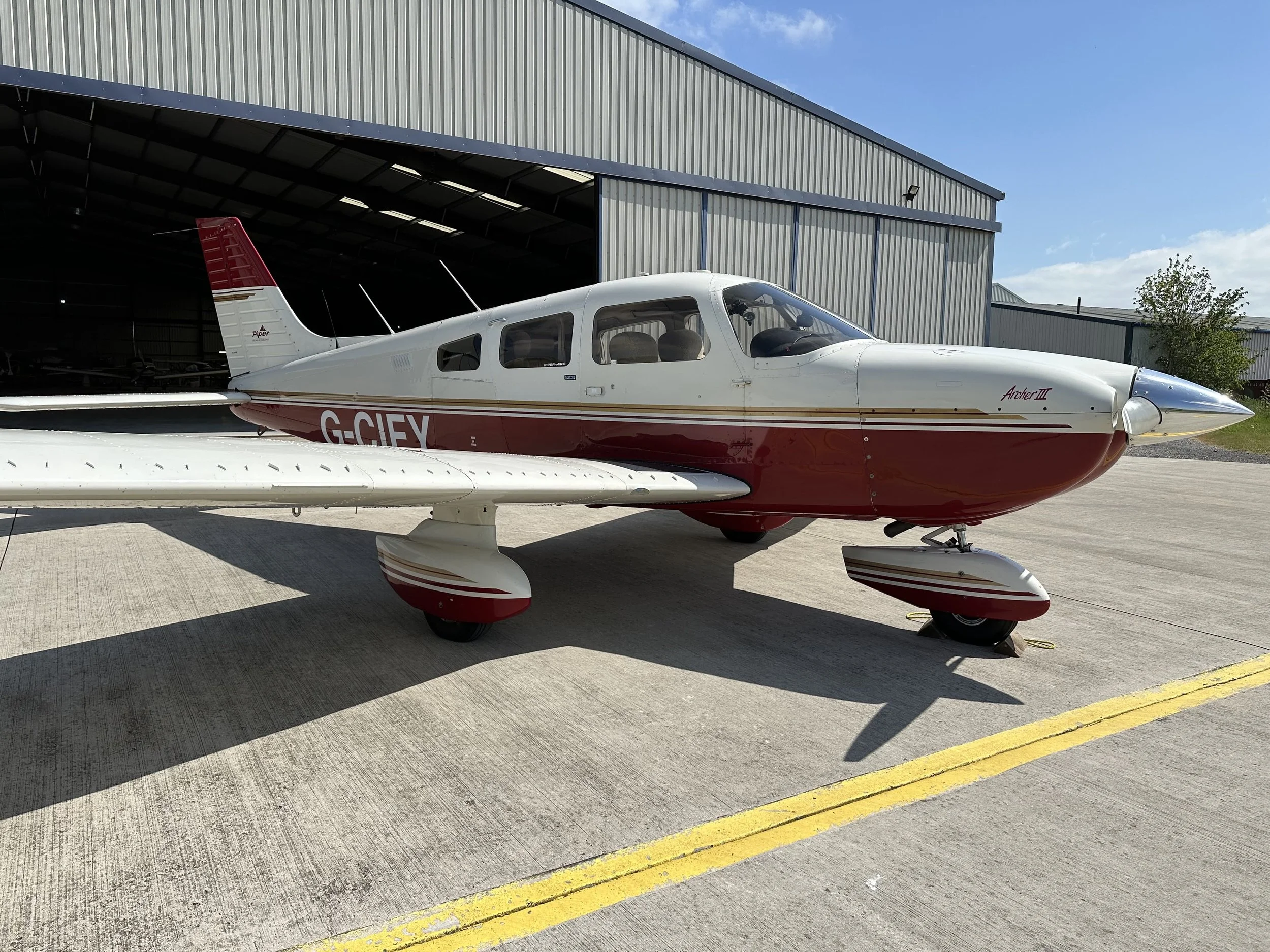 PA28 G-CIFY, A Piper Archer III airplane parked outside a hangar.