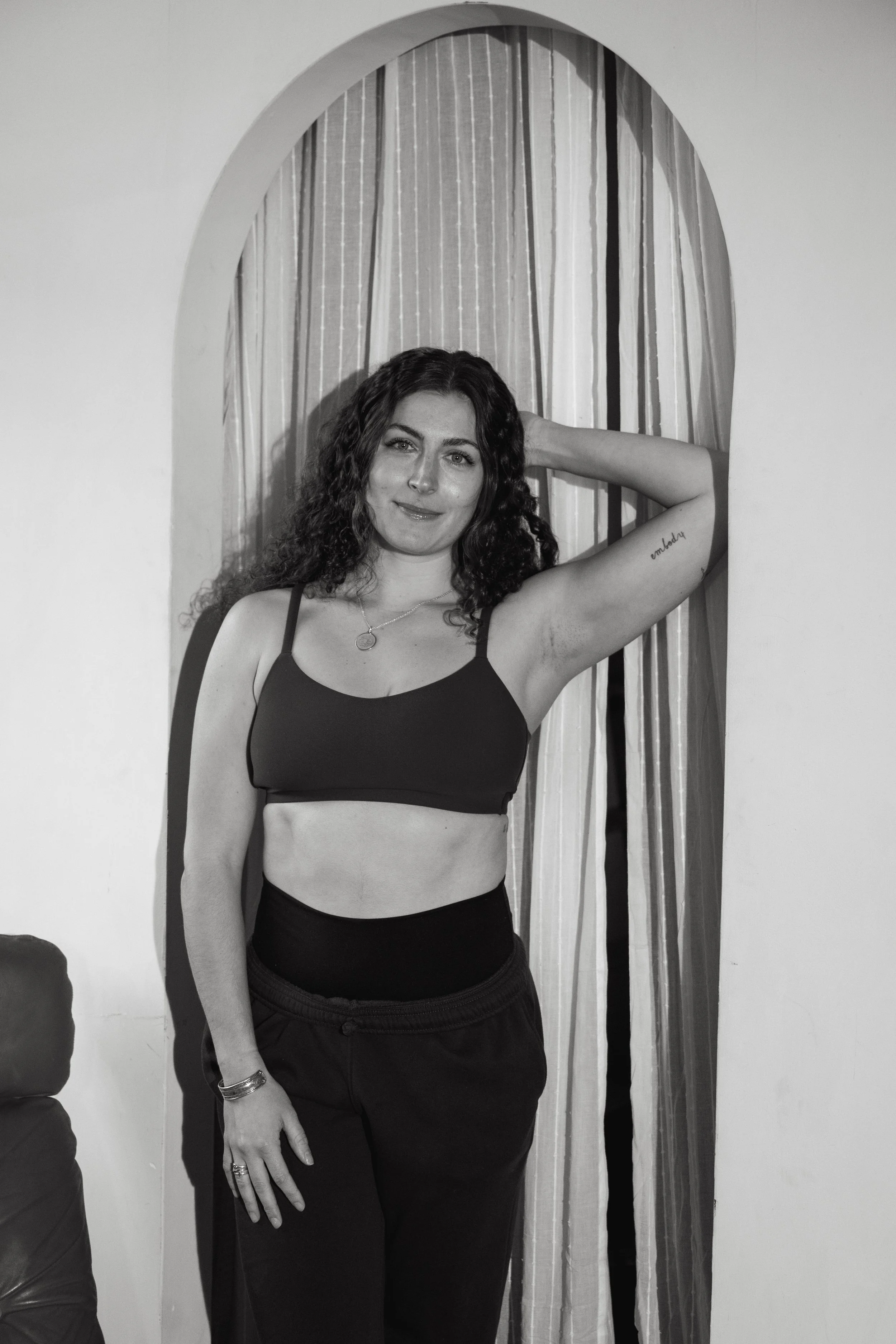 A black and white image of a yoga instructor standing in a doorway in a photo studio in Providence, Rhode Island.