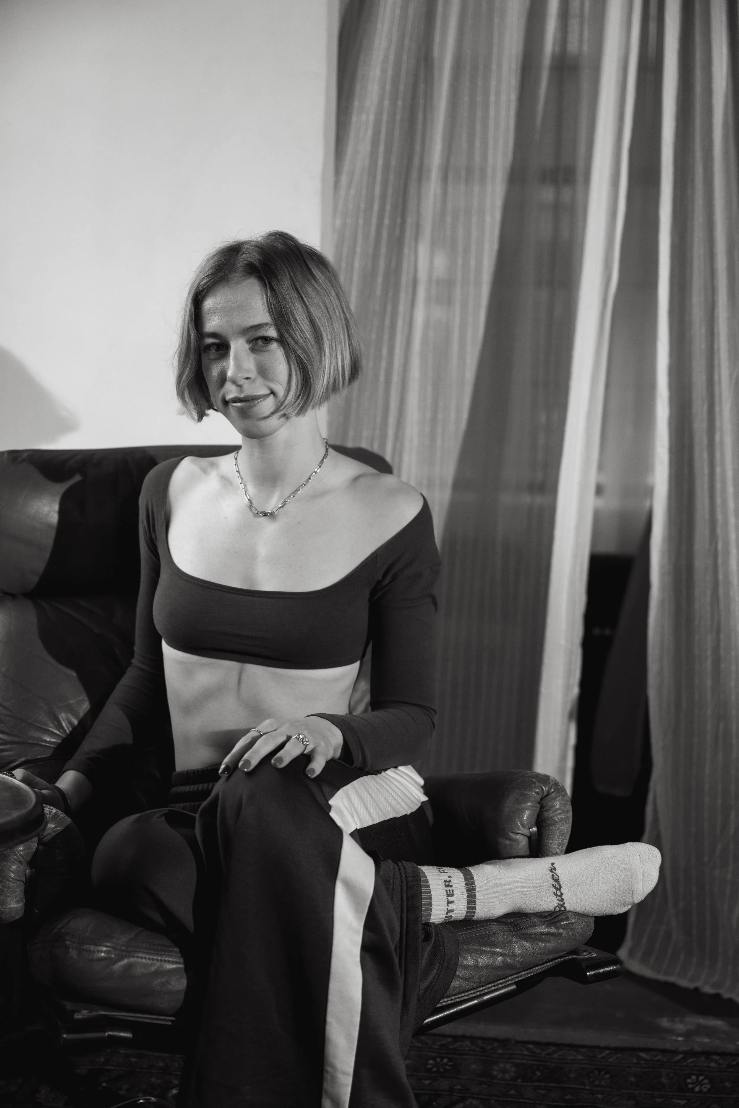 A black and white image of a yoga instructor sitting I a chair, posing for a headshot in a photo studio in Providence, Rhode Island.