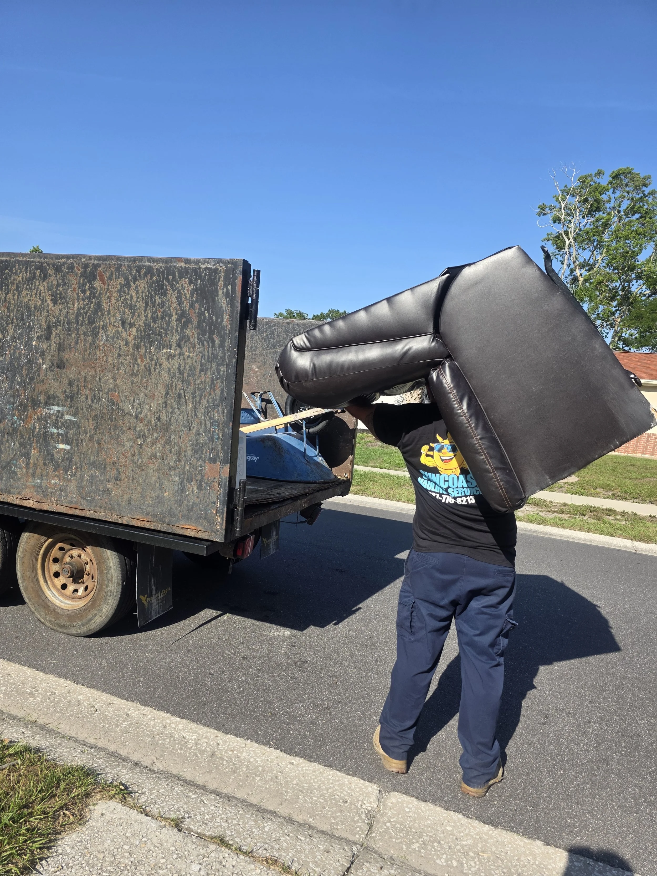Suncoast Hauling Services removing a couch during a furniture removal job in Palm Harbor, FL