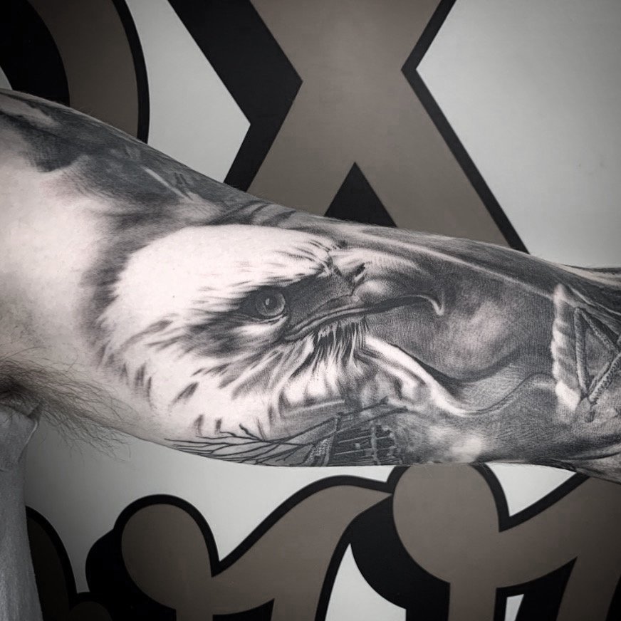 Black and gray tattoo of a fierce eagle with detailed feathers and intense eyes on a person's arm. Tattoo, tattoo artist, tattoos, realistic tattoo, portrait tattoo, artistic tattoo, experienced tattoo artist, Oregon, tattoo artist near me, nature ta