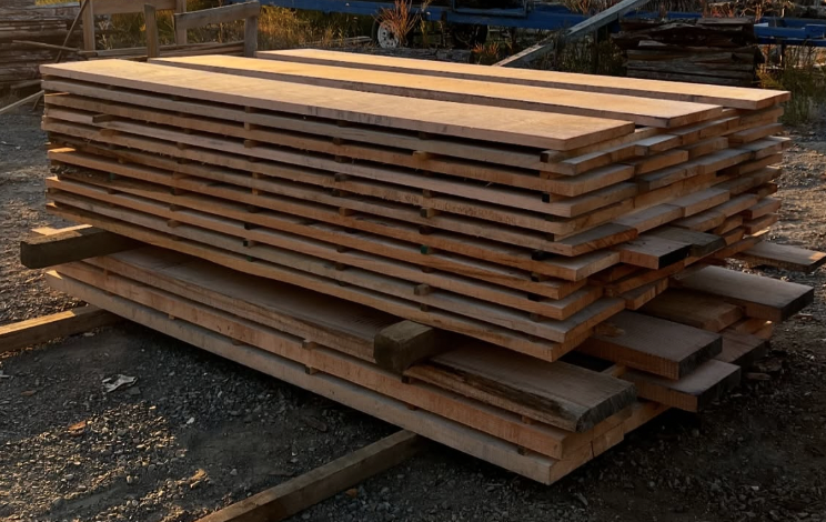 Stack of freshly cut wooden planks organized on a pallet outdoors.