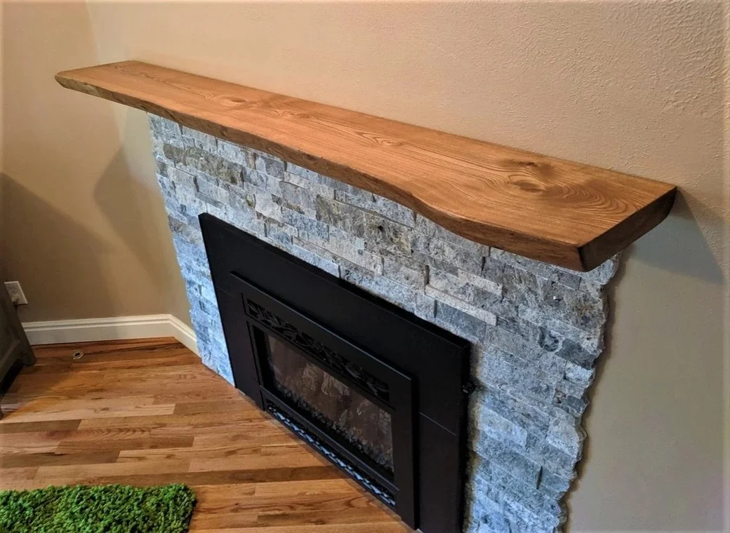 A fireplace with a stone surround and a wooden mantel.