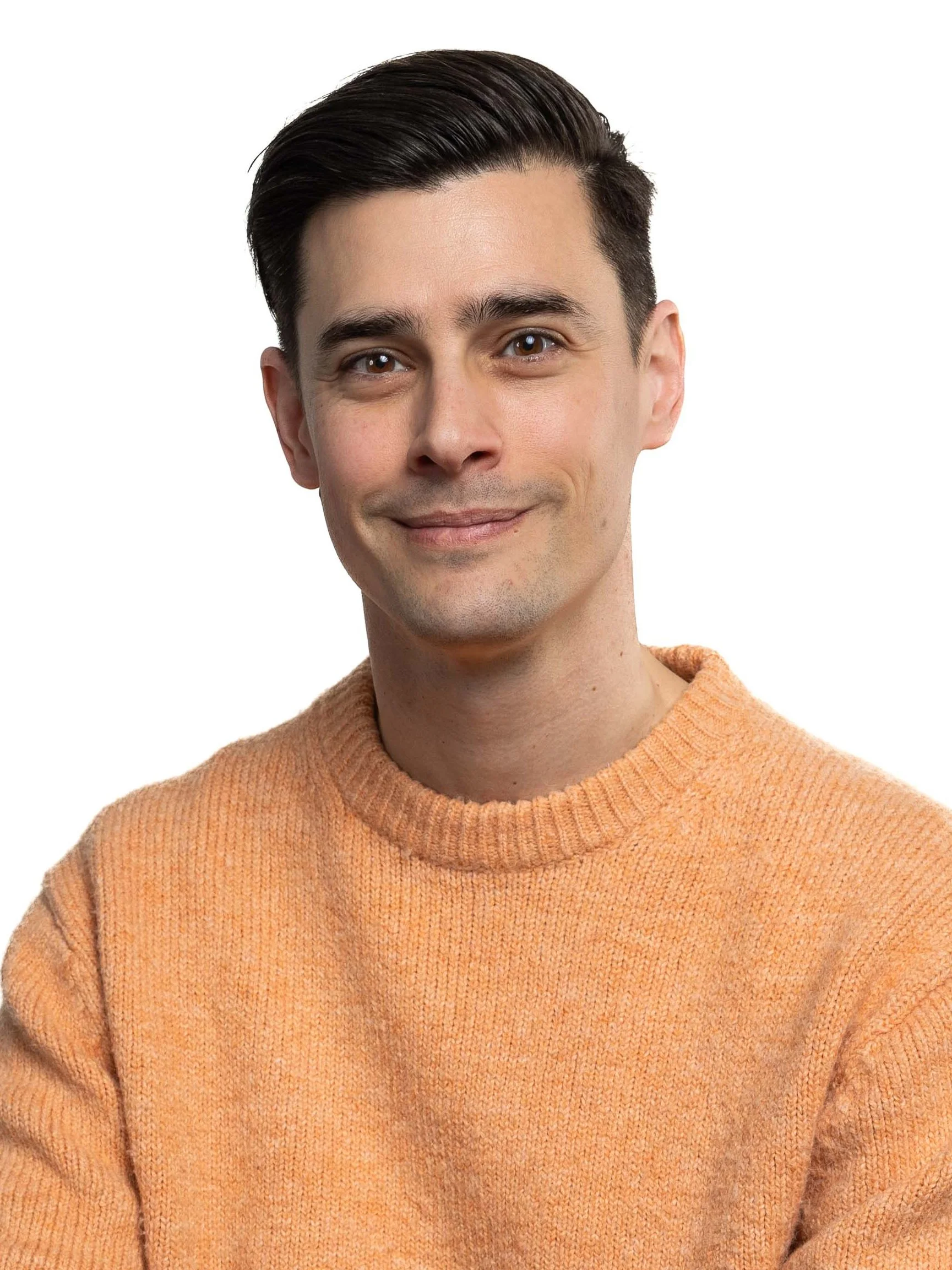 Portrait of a young man with dark, slicked-back hair, wearing an orange sweater, smiling slightly, against a white background.