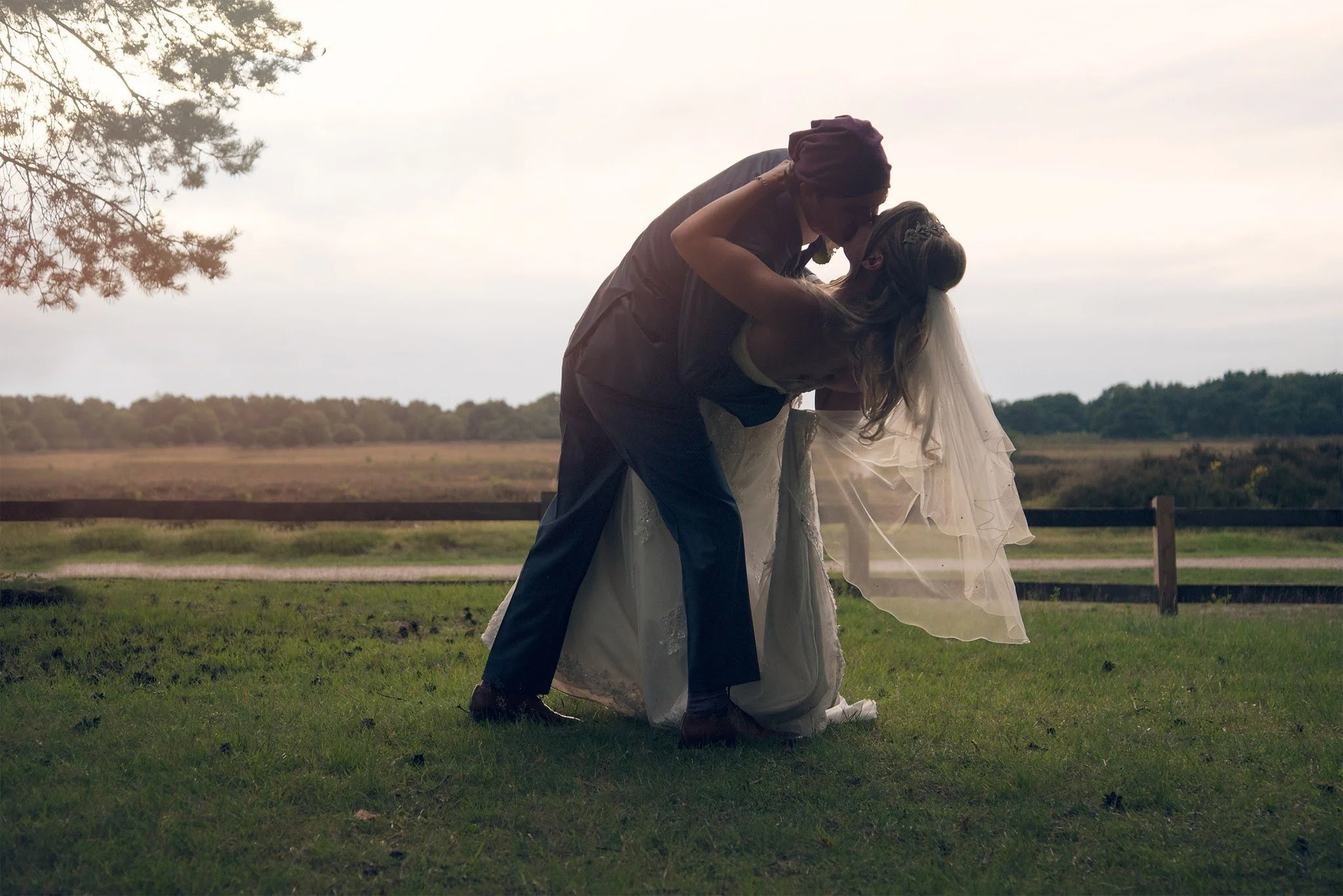 Een betoverende bruiloftsmoment: de bruidegom buigt zijn bruid romantisch achterover voor een liefdevolle kus, met een prachtig natuurlandschap op de achtergrond. Val Events maakt jullie droombruiloft werkelijkheid