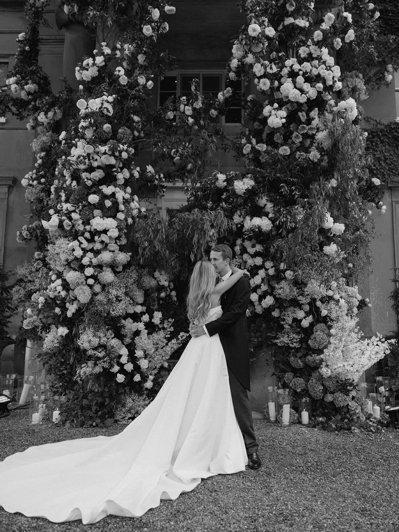 bride-groom-hugging-infront-of-wedding-arch-flowers.jpg