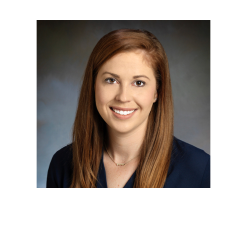 Professional headshot of a young woman with long red hair, wearing a dark navy blazer and smiling.