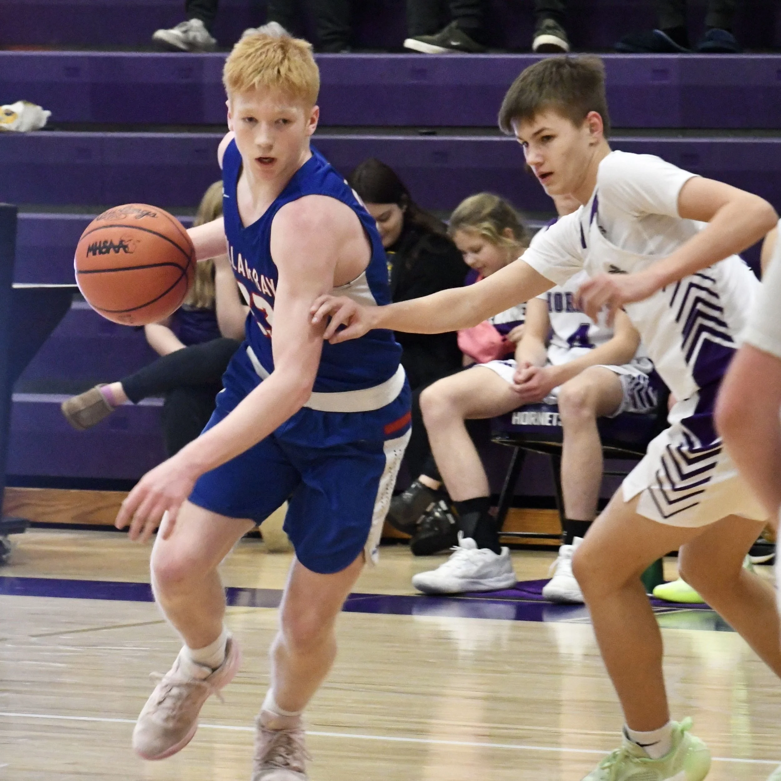 Junior varsity male, dropping his shoulder to dribble around his defender, hoping to penetrate the lane. 