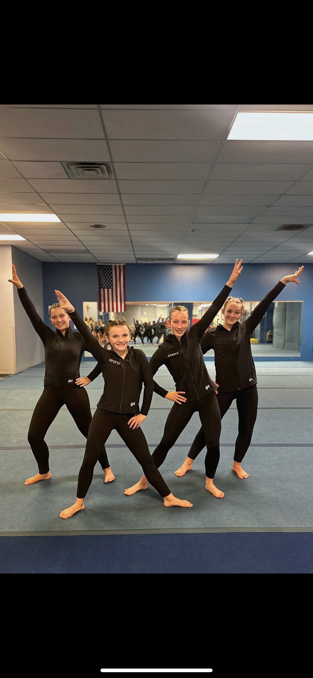 Dollar Bay gymnastics member on her toes with arms fully extended, in the middle of a floor mat performance. 