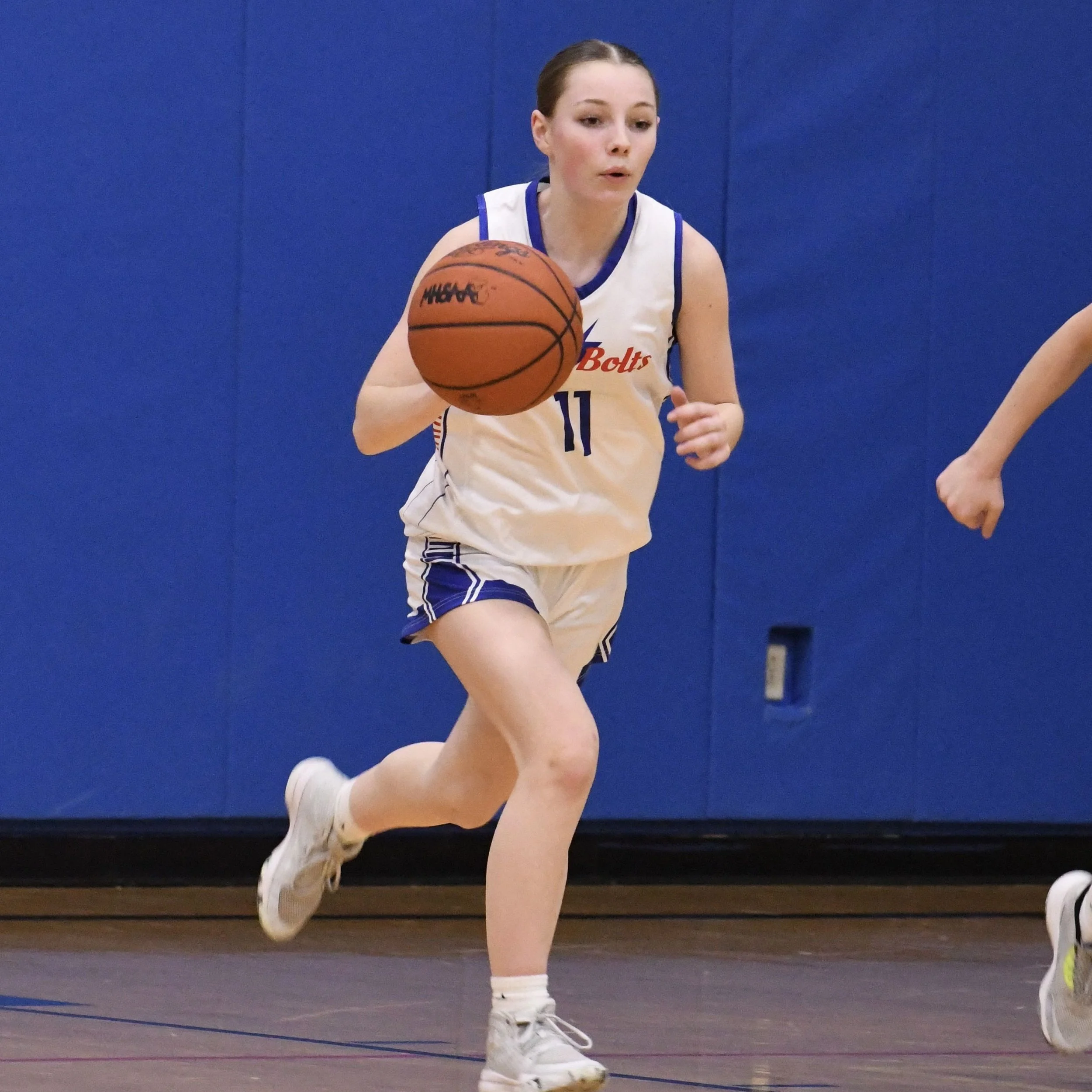 Junior varsity female racing the ball up the court from deep in the back court.