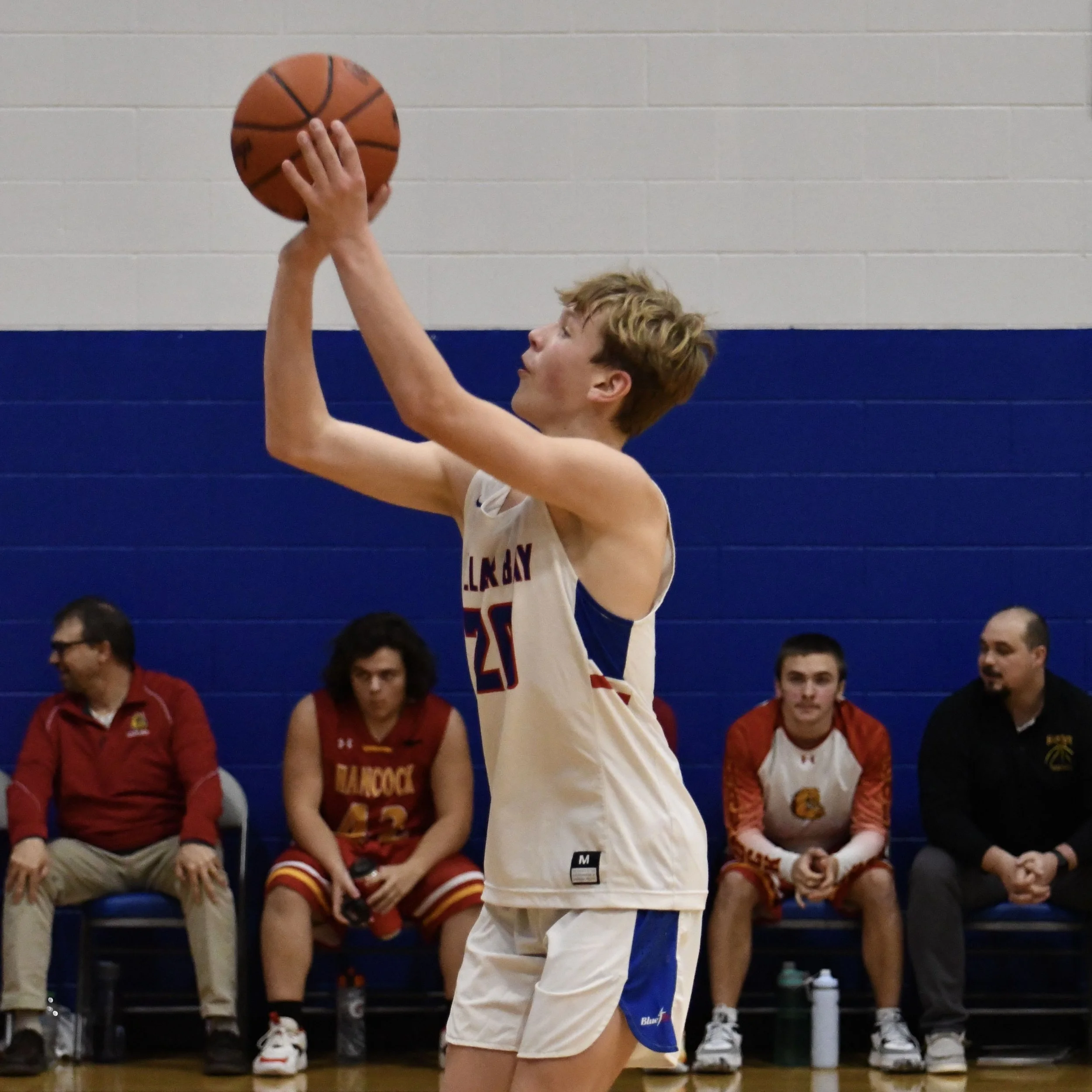 Junior varsity male, arms extended, about to release the ball on a free-throw.